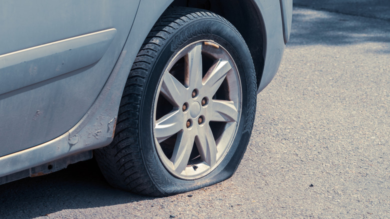 A car with a flat tire in a parking lot.