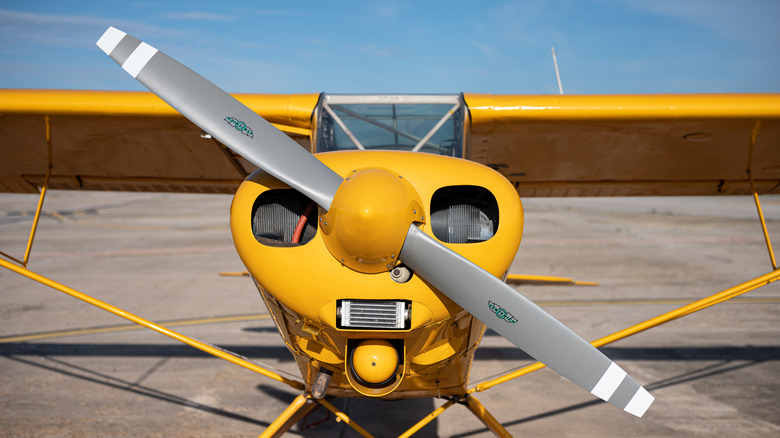 A grounded Piper PA-18 light high-wing aircraft in yellow