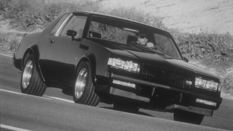 Front view of black Buick GNX driving on mountain road.