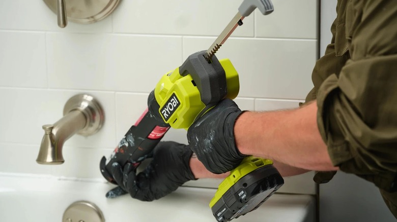 A person using a Ryobi Caulk Gun on a bathtub.