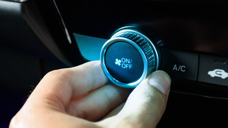 A person adjusting a car's fan dial