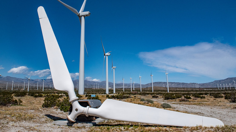 A decomissioned wind turbine against a background of functional ones
