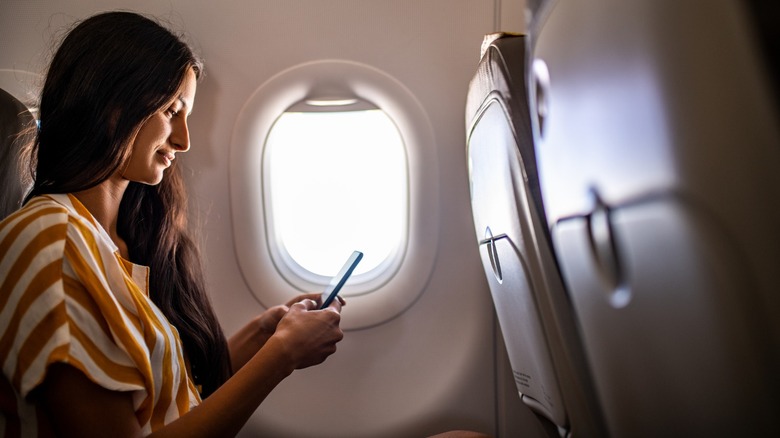 Woman using phone on an airplane