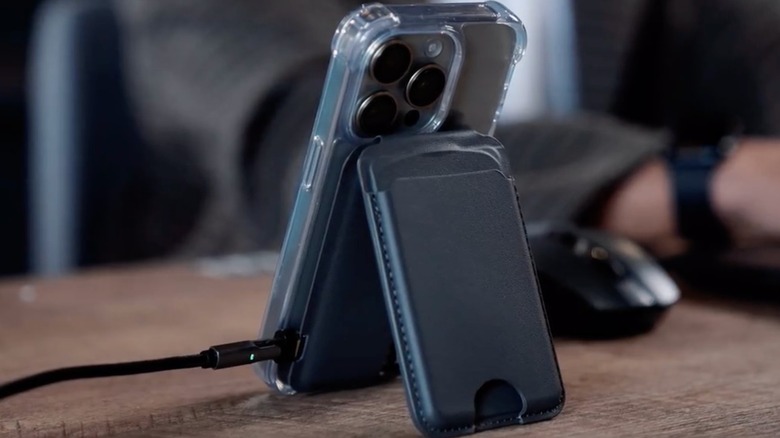 Black MagSafe charger-wallet on a desk, plugged to a black USB-C cable