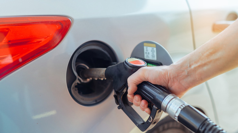 Close-up of attendant filling car with gasoline using gas pump nozzle