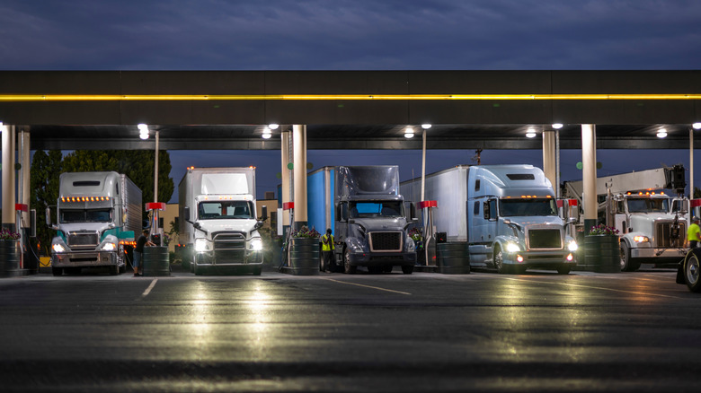 Truck stop gas station servicing five big rig trucks, front-view