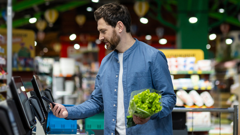 man using self-checkout for vegetables