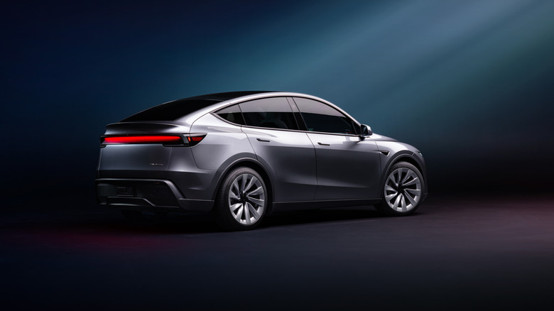 Rear 3/4 view of the Tesla Model Y Juniper in gray against a faint blue background