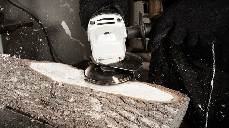 An angle grinder with an Arbortech blade shaves a log