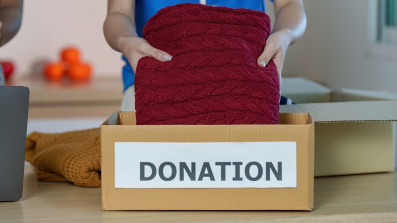 person putting sweater in donation box