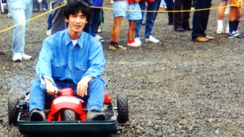A person riding the Mazda suitcase car on gravel
