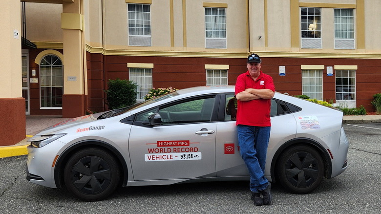 Wayne Gerdes standing next to his Toyota Prius outside a hotel, side view