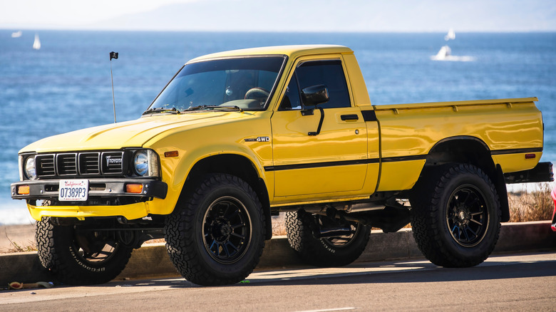 Front 3/4 view of a yellow 4x4 Toyota Truck parked at the beach.