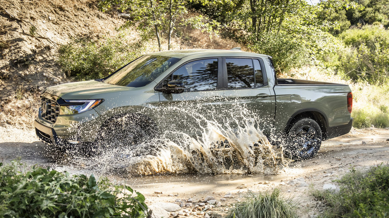 Side view of Honda Ridgeline splashing up water in off-road setting