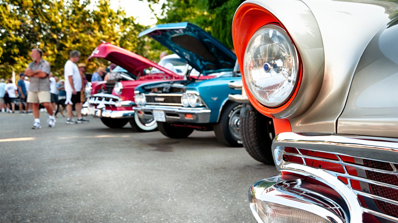 Several classic cars with open hoods at an open air clasic car show