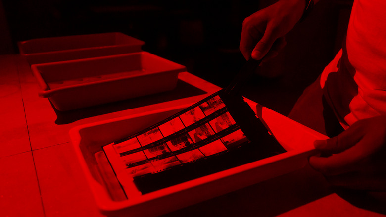 A tray of photo negatives being developed in a darkroom