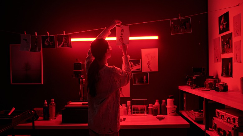 A person hanging developed photos to dry in a darkroom