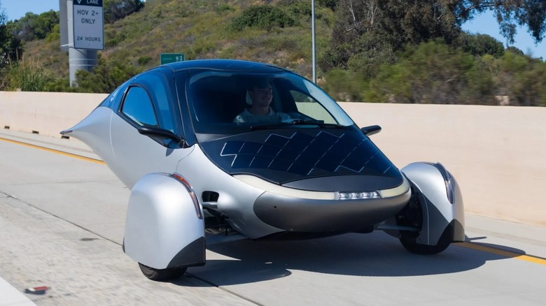 Aptera solar-powered EV driving on a California highway.