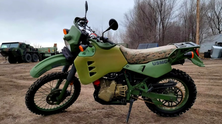 Kawasaki M1030-M1 standing on a muddy ground with another military vehicle behind