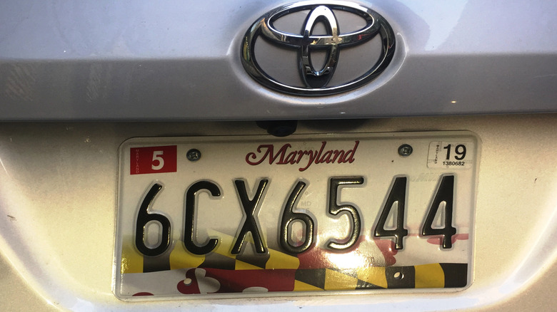 A license plate from Maryland on a silver Toyota.