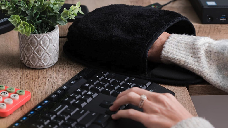 Woman using Wolvio heated mouse pad hand warmer while typing