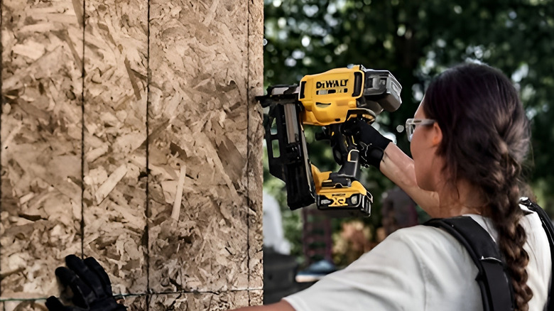 Woman using DeWalt nail gun outdoors on wall
