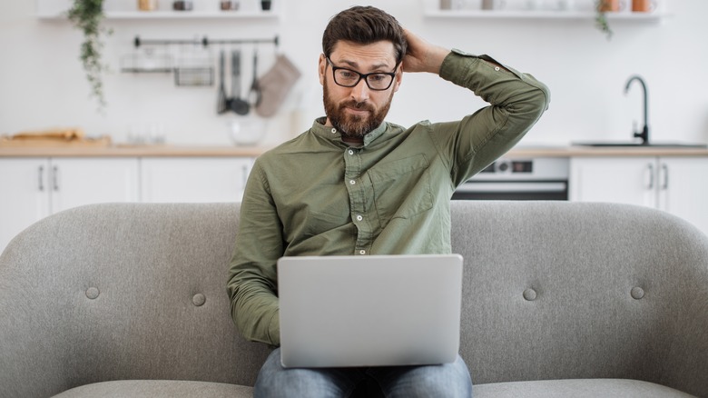 Hombre sentado en su sala de estar mirando la computadora portátil