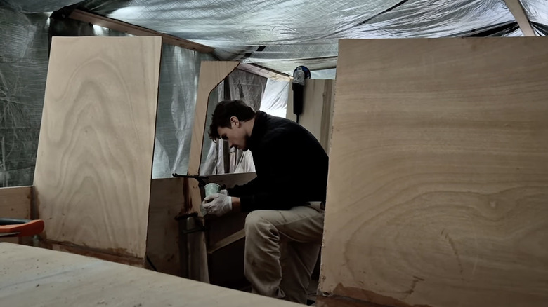 Man building solar yacht out of wood