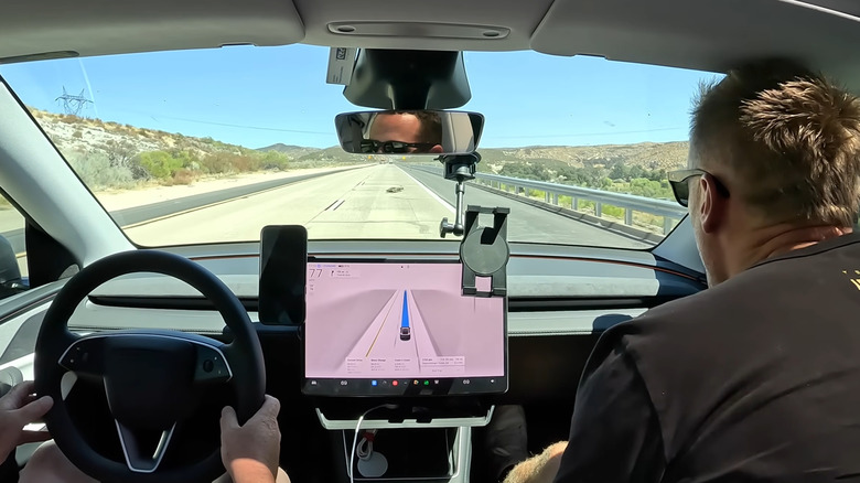 cockpit view of men in tesla driving on highway