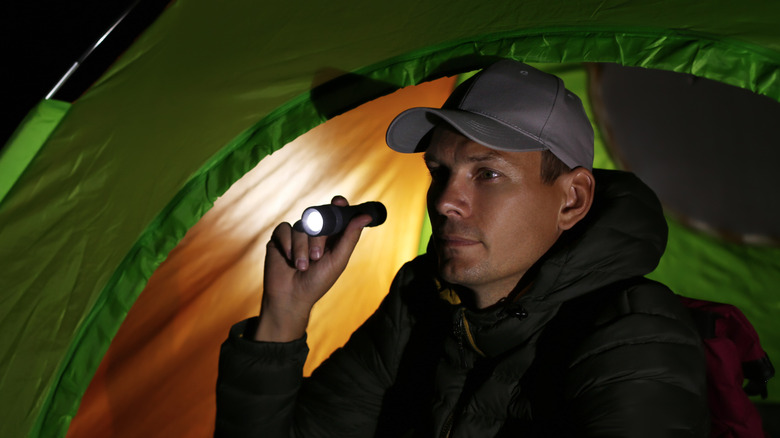 Man in tent with a small flashlight