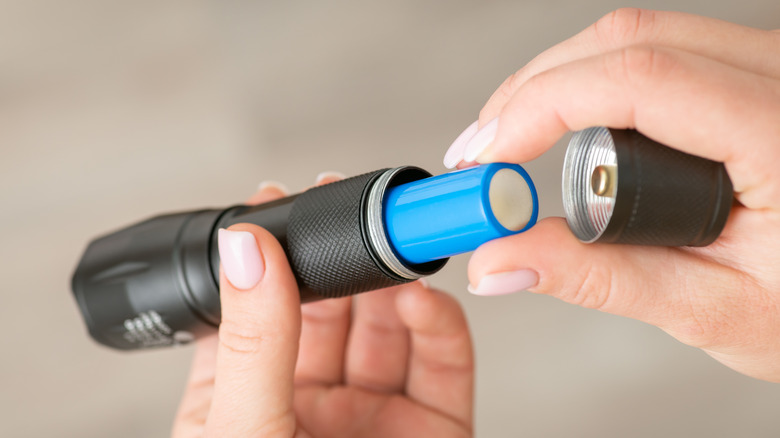 Person putting a battery into a portable flashlight