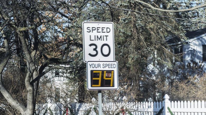 View through a speeding car's driver side windshield at a suburban New York State road