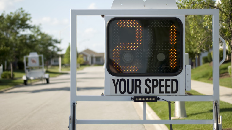A mobile police speed radar trailer sign showing 21 mph