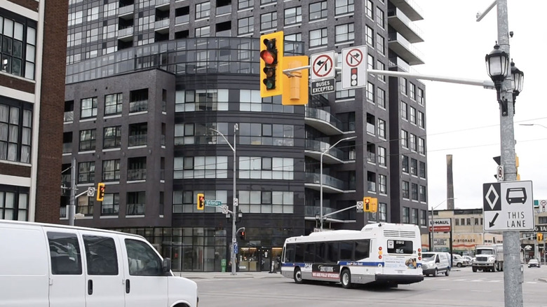 City intersection with a traffic light in the foreground and a bus turning left in the distance