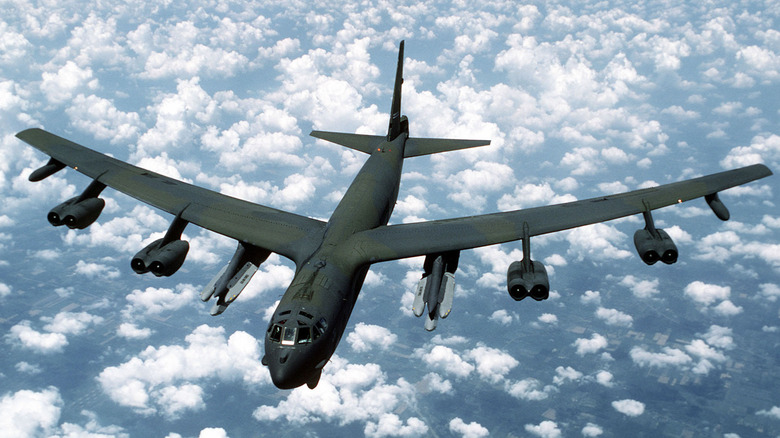 Un B-52G armado con misiles de crucero lanzados desde el aire volando sobre nubes rotas.