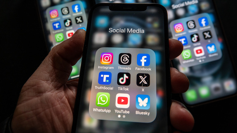 phone screen showing social media folder that includes X, Threads, and BlueSky