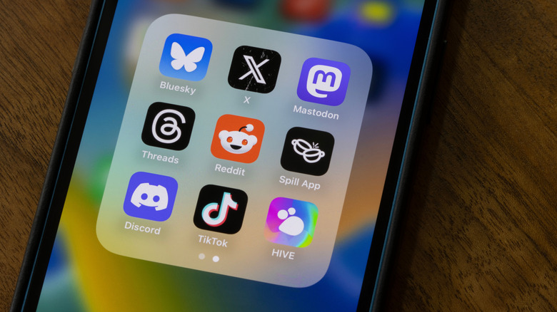 phone screen showing social media folder that includes X, Threads, and BlueSky