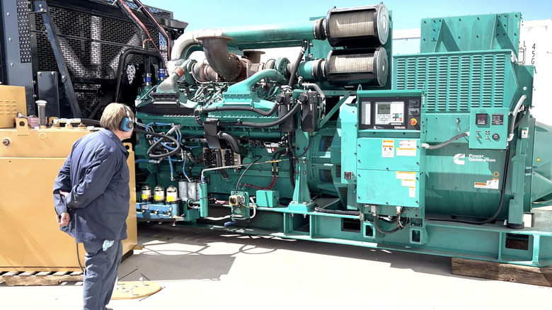 A man inspects a green Cummins 2500 kW diesel generator