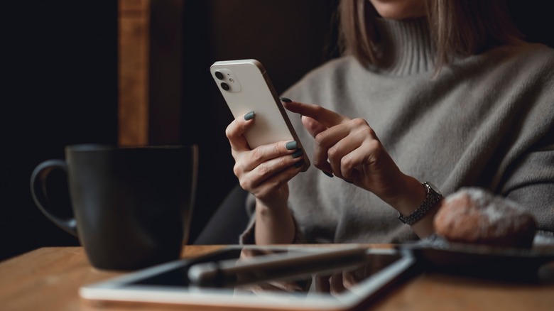 Person using iPhone 12 with iPad and Apple Pencil while at a table.