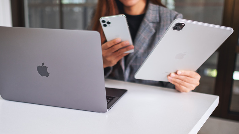 Person using iPhone 13 Pro Max, iPad Pro, and MacBook same time