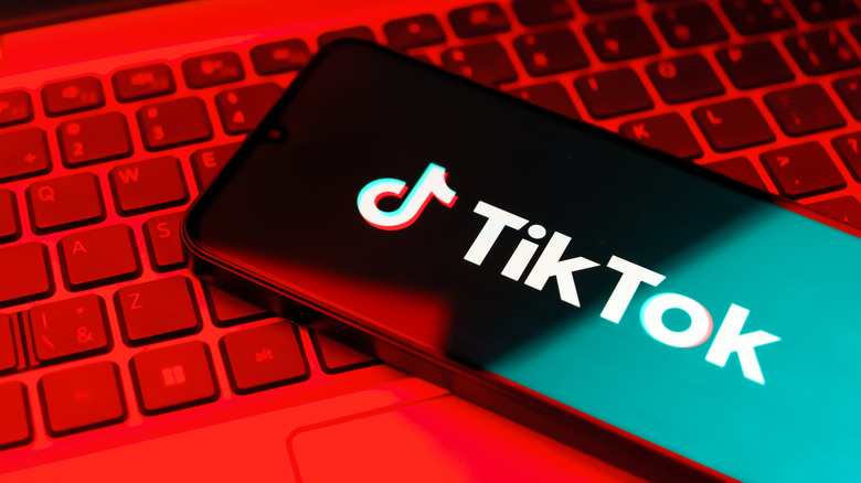 Phone with TikTok logo on red lit computer keyboard