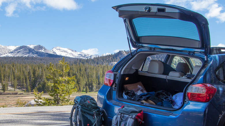 Rear view of open liftgate on blue Subaru Crosstrek with hiking gear.