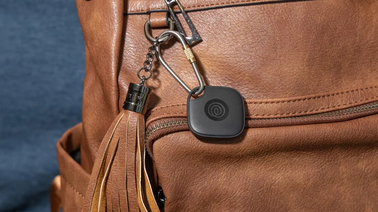 close-up of black Tile Mate tracker on a brown leather purse