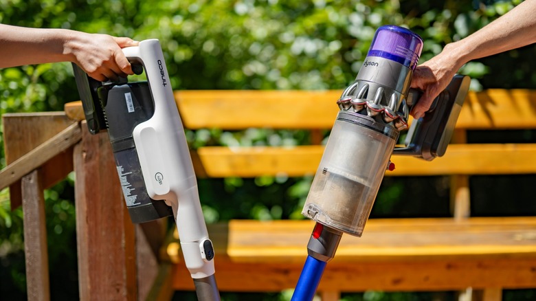 The Tineco Pure One Station 5 and Dyson V11 Origin next to each other outdoors.