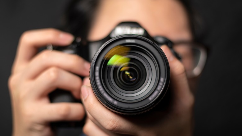 Person holding up lens of camera