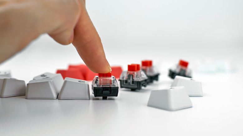 A person pushing down on a red mechanical switch