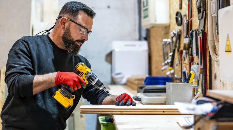 man screwing panel in workshop