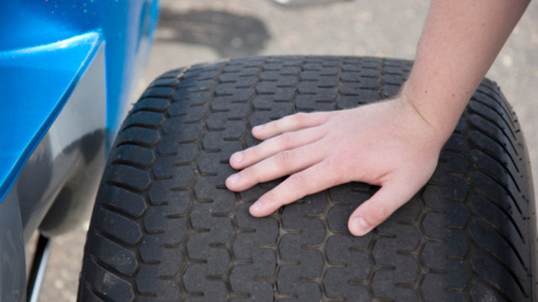 A person pressing their hand on a tire.