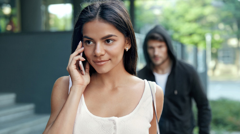 woman on phone man sneaks behind