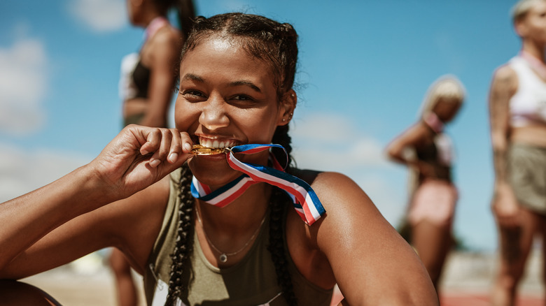 smiling female athlete biting medal 